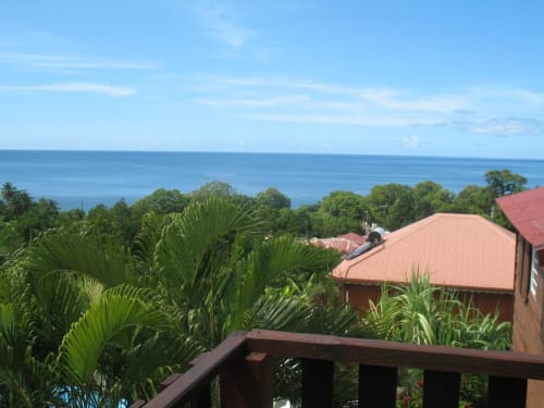 Art Lodge Kafé surplombant la mer des Caraïbes à Bouillante, Guadeloupe avec palmiers tropicaux et bungalows aux toits rouges