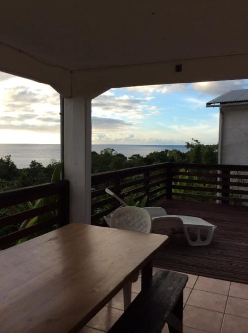 Terrasse avec vue sur l'océan à l'Art Lodge Kafé de Bouillante avec table de repas, balustrade et panorama marin