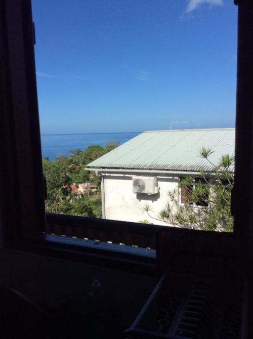 Vue sur l'océan depuis le Pavillon Corossol Haut à l'Art Lodge Kafé, Bouillante, avec son bâtiment aux toits blancs et la mer turquoise