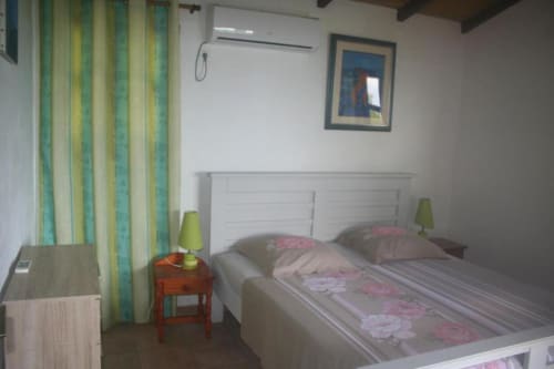 Chambre lumineuse à l'Art Lodge Kafé, Bouillante avec lit blanc, rideaux rayés verts et décor marin.