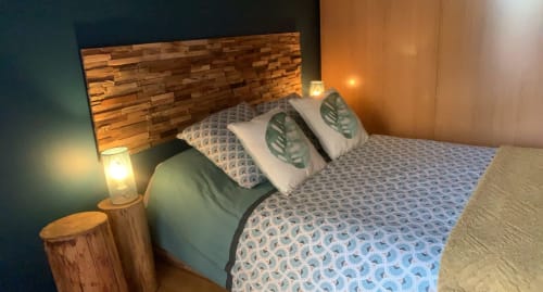Chambre chaleureuse aux Chambre D'hôtes Magaadjukalo avec tête de lit en bois, literie motifs, coussins décoratifs et ambiance douillette