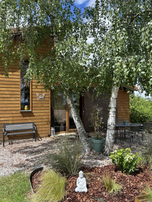 Chalet en bois avec bouleaux retombants, bancs et terrasse jardin de la Chambre d'hôtes Magaadjukalo