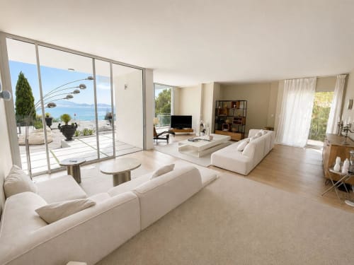 Villa spacieuse JFK à Marseille, salon lumineux avec vue mer, mobilier crème, TV moderne et accès direct à la plage par baies vitrées