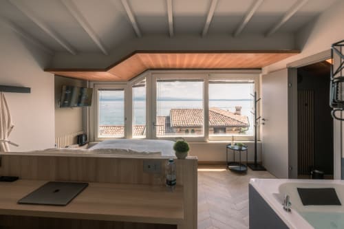 Lussuosa camera con vista sul lago di Como a Casa Giulietta, vasca moderna, scrivania e finestre panoramiche che si affacciano su Sirmione.