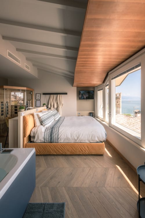 Camera boutique presso Casa Giulietta a Sirmione con soffitto in legno, vista lago e arredamento moderno affacciato sul Lago di Como