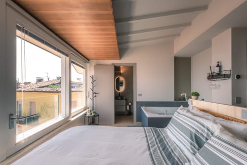 Camera moderna a Casa Giulietta Como con vista sul lago, soffitto in legno, biancheria a righe e bagno privato