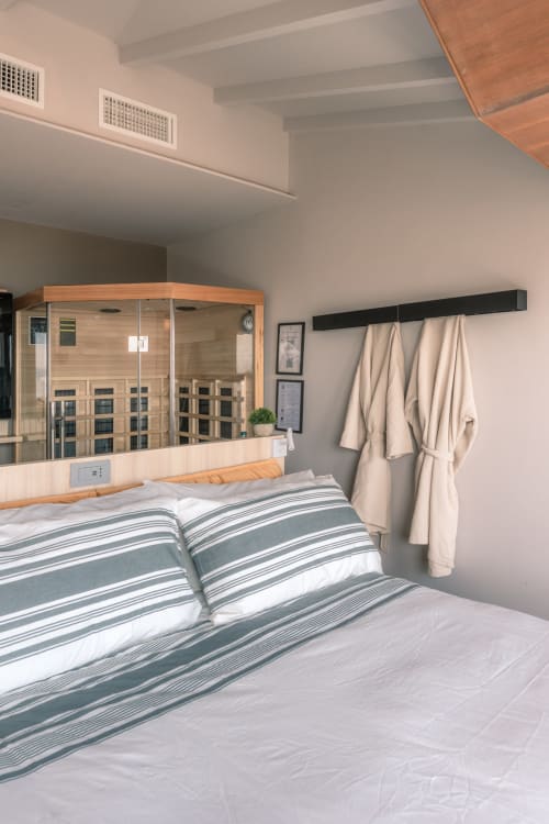 Camera moderna con biancheria a righe, sauna in legno, accappatoi beige e vista sul lago presso l'hotel boutique Casa Giulietta a Como,