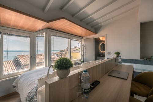 Camera boutique Casa Giulietta a Sirmione con vista sul lago di Como, dettagli del soffitto in legno e arredi moderni