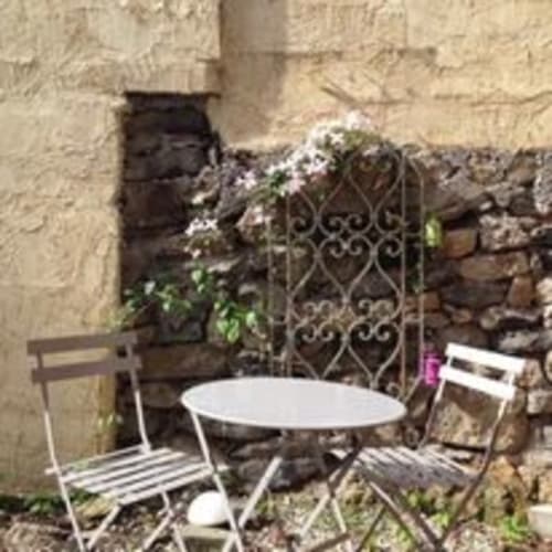Espace de détente extérieur cosy avec chaises bistrot blanches et table ronde dans ce gîte français à Saint-Maurice-de-Lignon