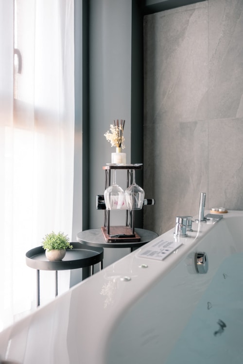 Bagno moderno a Casa Giulietta Sirmione con tavolini rotondi neri, lavabo bianco e finestra con vista sul lago di Como