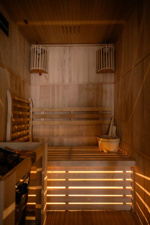 Lussuoso interno di sauna in legno a Casa Giulietta a Como, Italia, con illuminazione d'atmosfera e sedute tradizionali