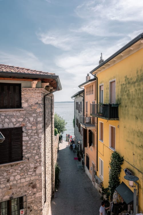 Stretta via italiana a Sirmione con edifici gialli e in pietra che si affacciano sul lago di Como