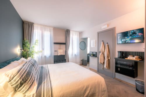 Camera da letto moderna e luminosa a Casa Giulietta a Como con letto queen, TV a schermo piatto, pavimenti in legno e vista sul lago