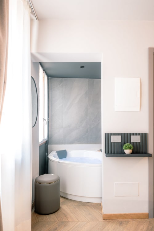 Vasca idromassaggio moderna nella camera Casa Giulietta, Como, con rivestimento in piastrelle grigie e pavimento in legno