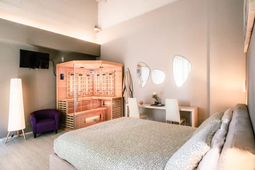 Camera moderna a Casa Giulietta Como con sauna in legno, letto queen, poltrona viola, specchi per il trucco e TV a schermo piatto