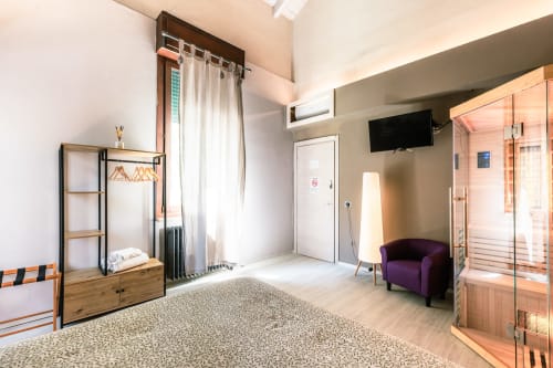 Camera Lilly all'hotel Casa Giulietta Como con pavimenti in legno, poltrona viola, accesso alla sauna e comfort moderni