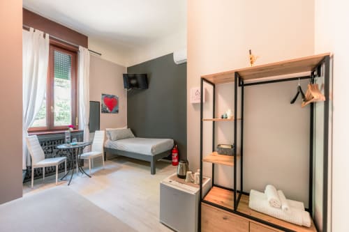 Camera d'hotel moderna a Casa Giulietta Como con letto, armadio, TV, scrivania, finestra con vista sulla città e arredamento contemporaneo