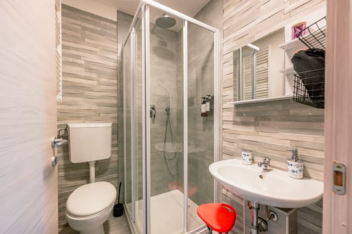 Bagno moderno nella camera dell'hotel Casa Giulietta con doccia, lavabo, wc e pareti in legno e piastrelle a Como