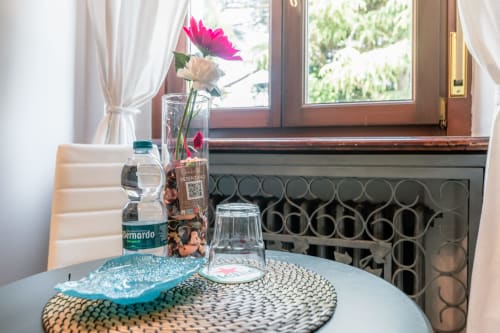 Dettaglio della camera d'hotel a Casa Giulietta Como con fiori, bottiglia d'acqua e finestra con vista sulla città