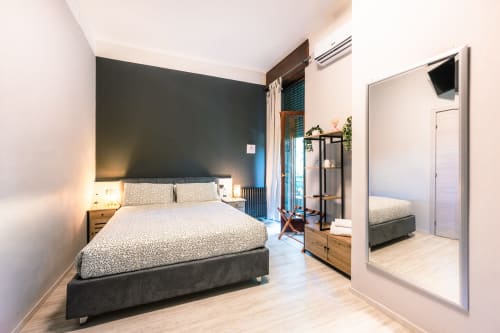 Camera moderna a Casa Giulietta a Como con parete d'accento scura, letto queen, pavimento in legno, specchio e stile contemporaneo