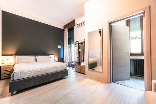 Camera moderna a Casa Giulietta Como con parete d'accento scuro, letto queen, pavimenti in legno e vista del bagno en suite
