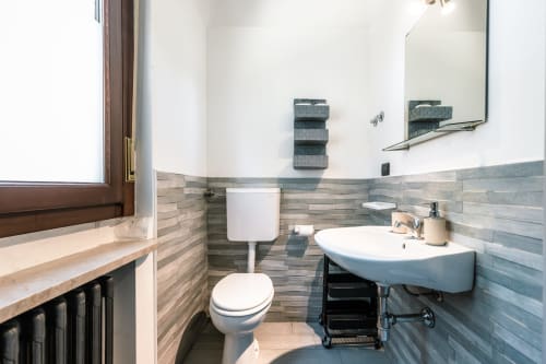 Bagno moderno a Casa Giulietta, Como con pareti piastrellate, lavabo bianco, wc, specchio e finestra