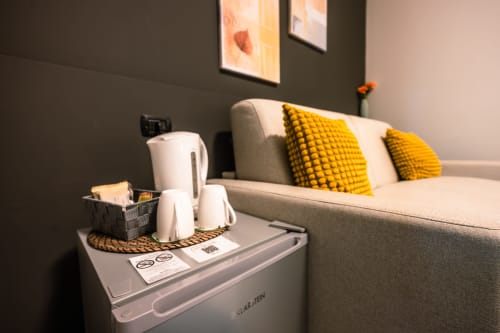Camera d'albergo moderna a Casa Giulietta Como con divano beige, cuscini gialli e vassoio di benvenuto