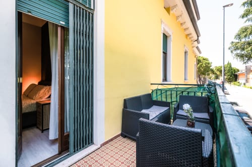 Balcone con sedute in vimini nero presso l'hotel Casa Giulietta a Como, Italia, affacciato su edificio di colore giallo