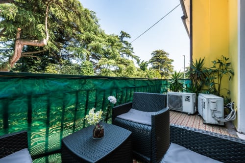 Balcone della camera Sunflower a Casa Giulietta, Como - mobili in vimini nero con vista sul lago e schermo di privacy verde