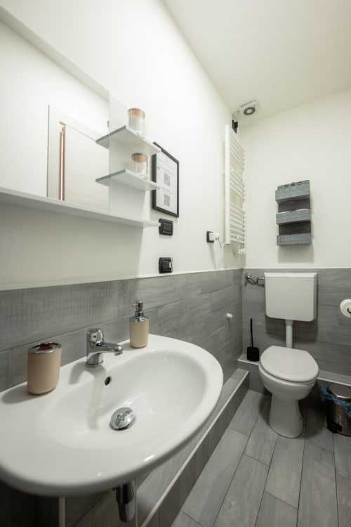 Bagno moderno della camera d'albergo Casa Giulietta Como con lavabo rotondo, WC, piastrelle grigie e mensole a muro
