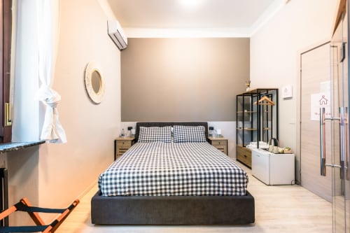 Camera moderna a Casa Giulietta Como con biancheria a quadri, comodini in legno e arredamento contemporaneo