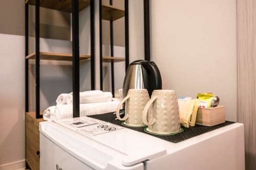 Dettaglio della camera d'hotel a Casa Giulietta Como: bollitore elettrico, tazze in ceramica e articoli da toilette omaggio sulla scrivania