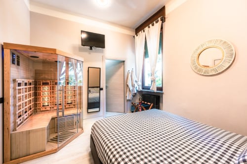 Camera moderna a Casa Giulietta Como con sauna, letto a quadri, TV a schermo piatto e arredamento in legno