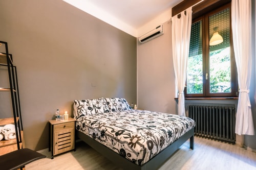 Camera Viola a Casa Giulietta, Como - Letto matrimoniale con biancheria a motivi, finestra con vista sul lago, aria condizionata, legno