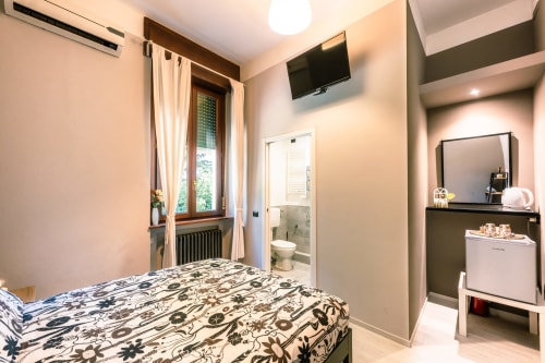 Camera Viola presso Casa Giulietta Como: camera da letto con biancheria a motivi, TV, bagno privato, vanity e vista sul lago.