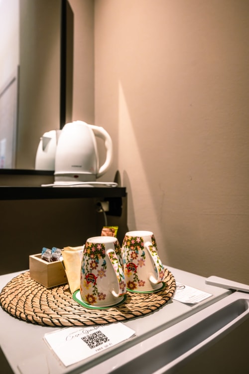 Tavolino da notte decorato a Casa Giulietta Como con tazze floreali, comfort di benvenuto e bollitore elettrico per il servizio di tè