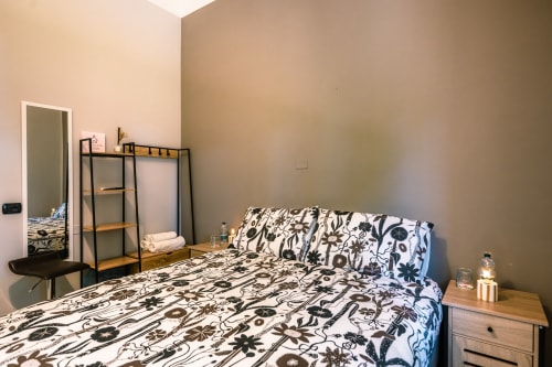 Accogliente camera da letto a Casa Giulietta, Como con biancheria floreale bianca e nera, comodino in legno e specchio
