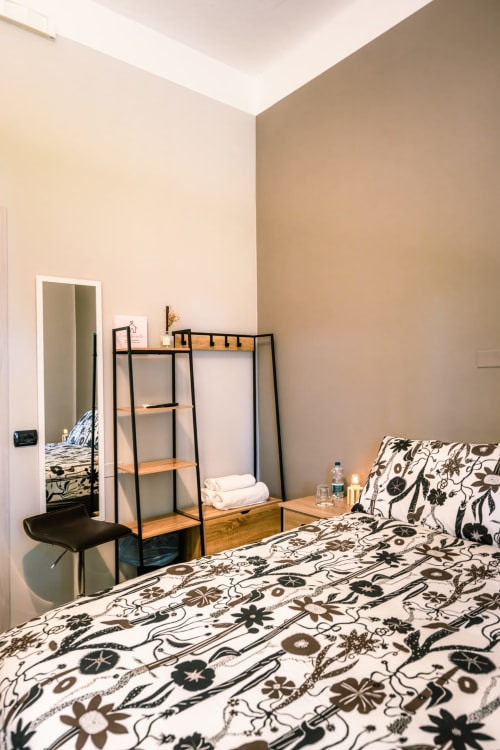 Camera moderna a Casa Giulietta Como con biancheria da letto a motivi, scaffalatura metallica nera e arredamento minimalista