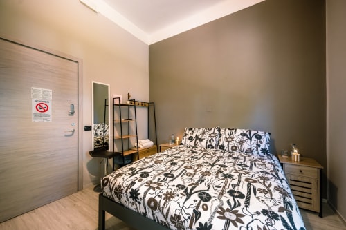 Camera Viola presso Casa Giulietta, Como - camera da letto moderna con biancheria a motivi, pavimento in legno e arredamento contemporaneo