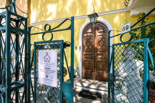 Ingresso dell'hotel Casa Giulietta a Como con cancellata turchese, porta in legno e facciata gialla
