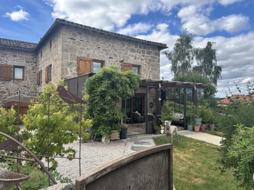 Maison en pierre avec extension vitrée moderne et terrasse de jardin au gîte Magaadjukalo à Saint-Maurice-de-Lignon, France
