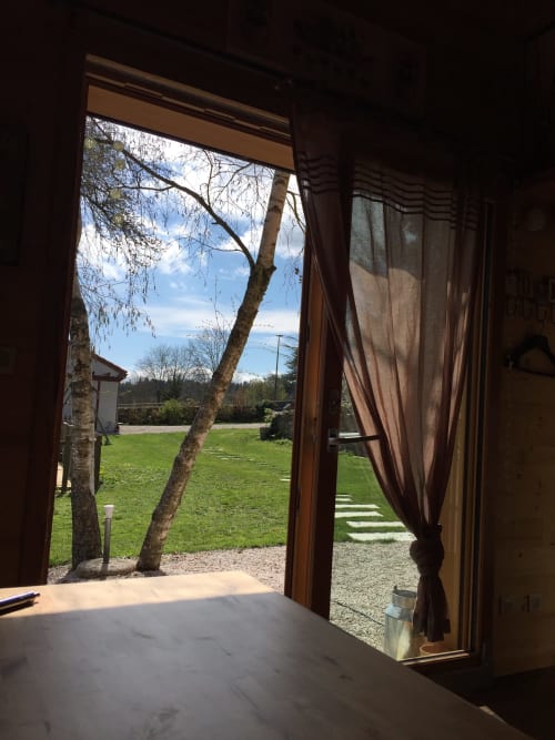 Vue de la terrasse du gîte avec portes ouvertes sur les jardins verdoyants et bouleau de l'écolodge Les Papillons des Sucs