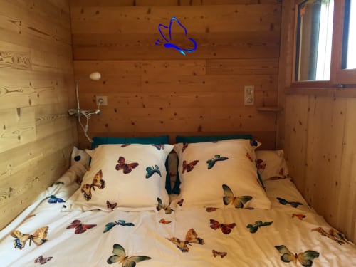 Chambre douillette aux motifs papillons, murs en bois et enseigne néon chez Les Papillons Des Sucs