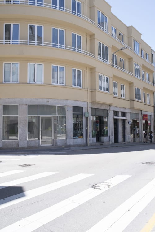 Modern apartment building in downtown Porto with ground floor shops, curved balconies, and pedestrian crossing