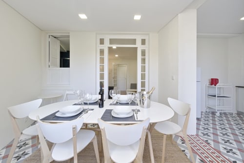 Sala de jantar moderna com mesa redonda branca e cadeiras no apartamento Aveiro com Paixão Living Porto
