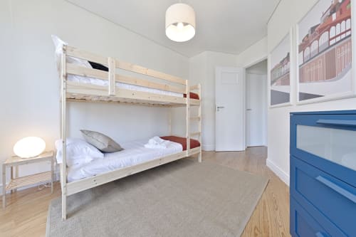 Modern bunk bed bedroom in downtown Porto apartment with wooden flooring, city views, and blue furniture