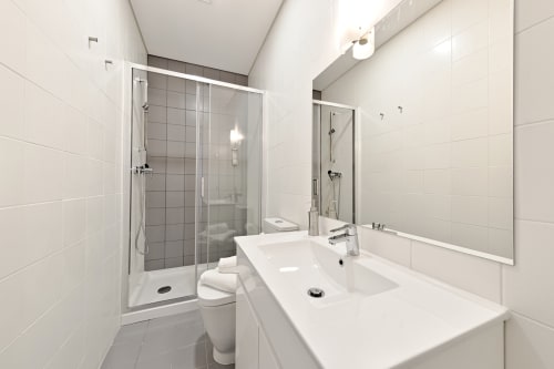 Casa de banho moderna com azulejos subway brancos, bacia dupla, chuveiro walk-in e espelho no apartamento do Porto