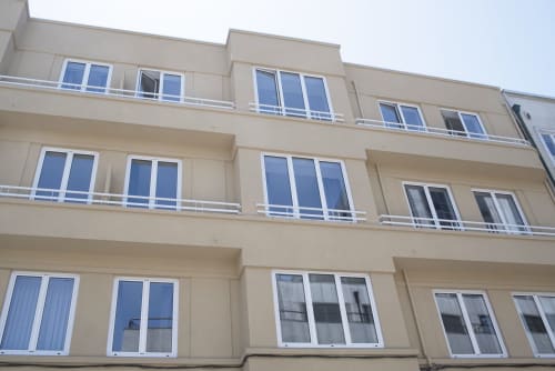 Beige apartment building facade with multiple windows and balconies in Porto city center