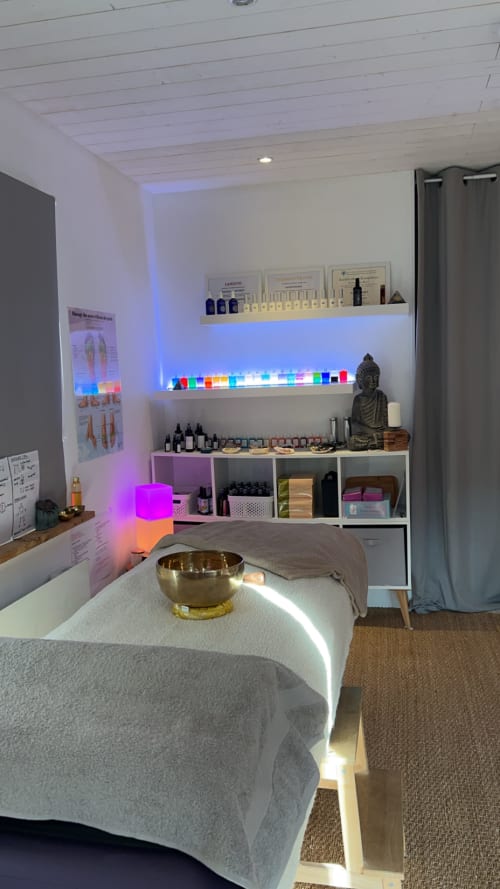 Salle de soins spa moderne avec étagères illuminées présentant des produits bien-être et une statue de Bouddha à la Chambre D'hôtes