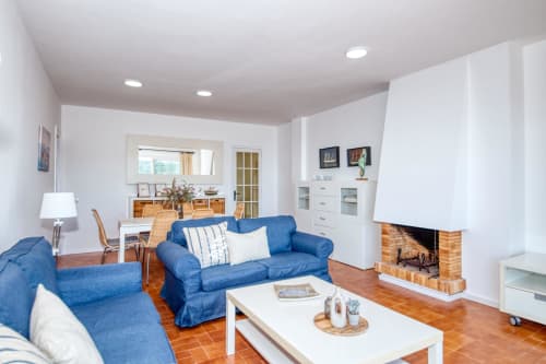 Saló brillant amb sofàs blaus, llar de foc i zona menjador a Finques Garcia Enrich, Palafrugell